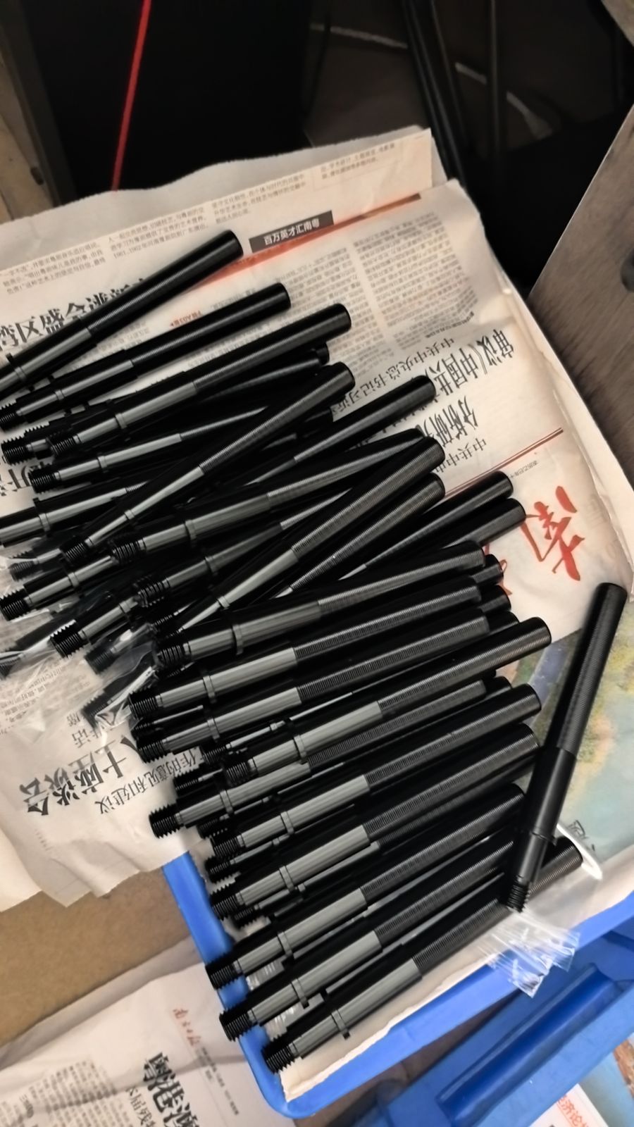 Batch of slender threaded shafts with black oxide finish