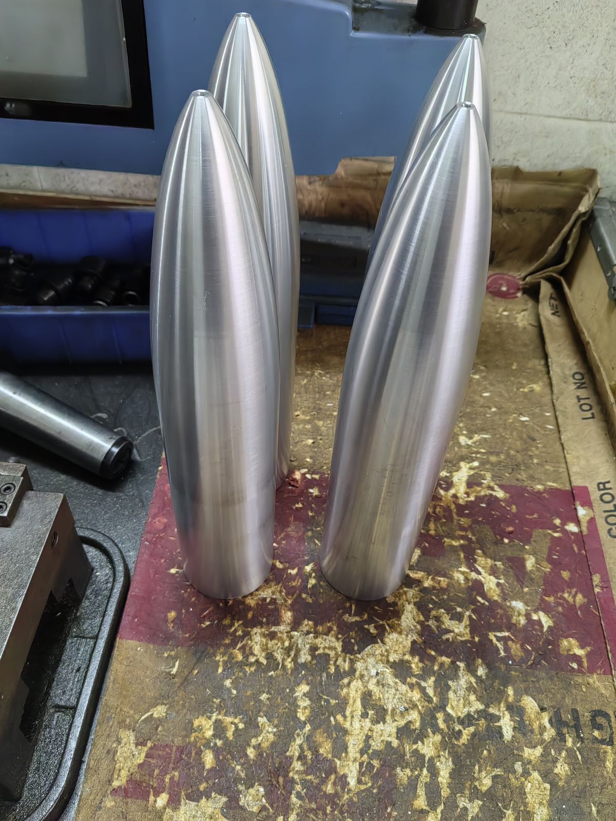 Four polished stainless steel torpedo-shaped parts