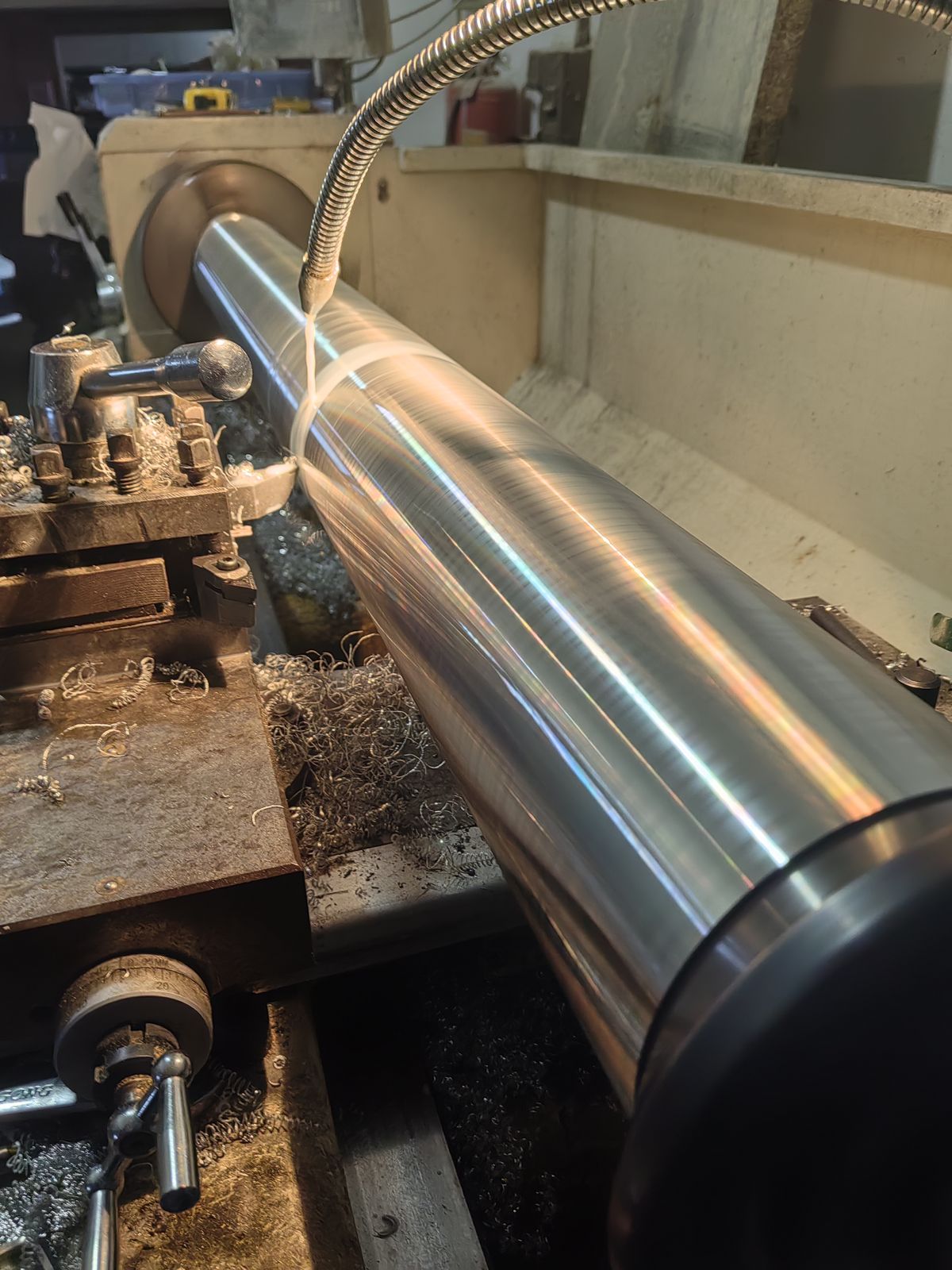 Mirror-finish long steel shaft being turned on a lathe